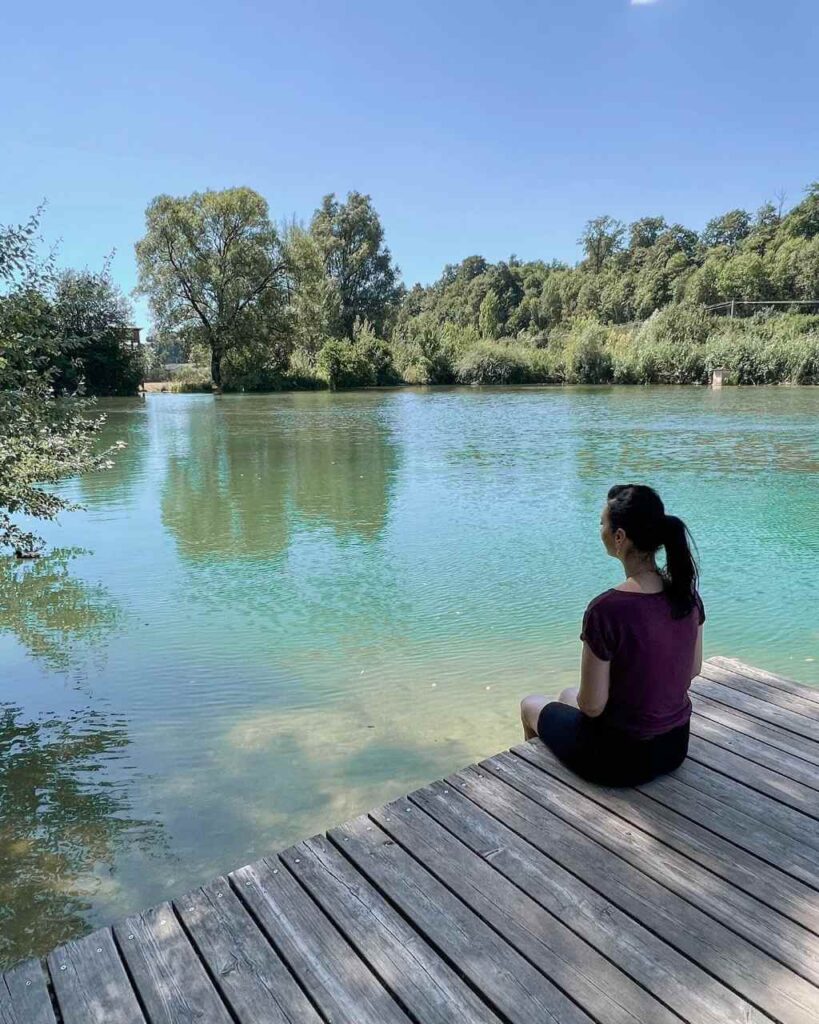 Eine Frau sitzt am Steg am Ufer des Lonesees auf der Schwäbischen Alb