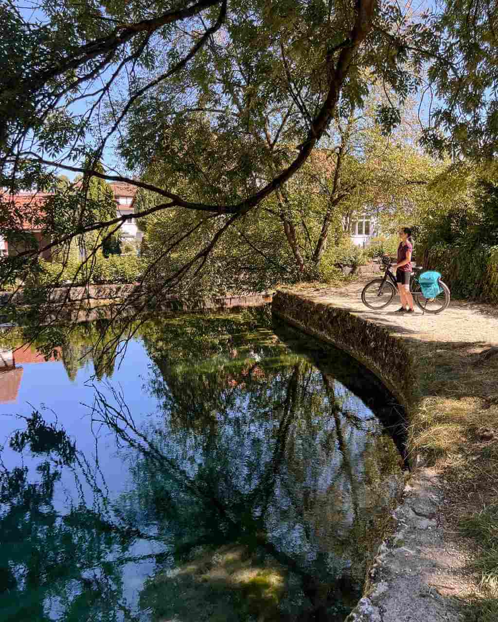 Eine Radfahrerin steht am Ufer des Lonetopfs auf der Schwäbischen Alb.