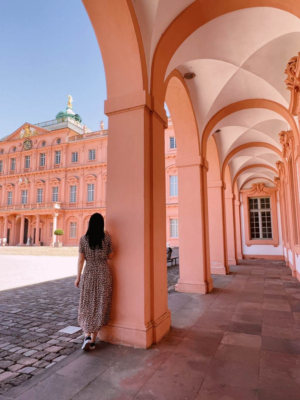 Eine Frau steht in den Arkaden des barocken Schlosses Rastatt