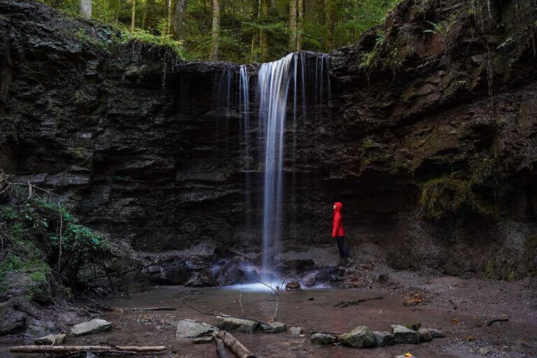 Ausflugsziele Stuttgart: eine Frau steht unter dem Hörschbachwasserfall im Wald