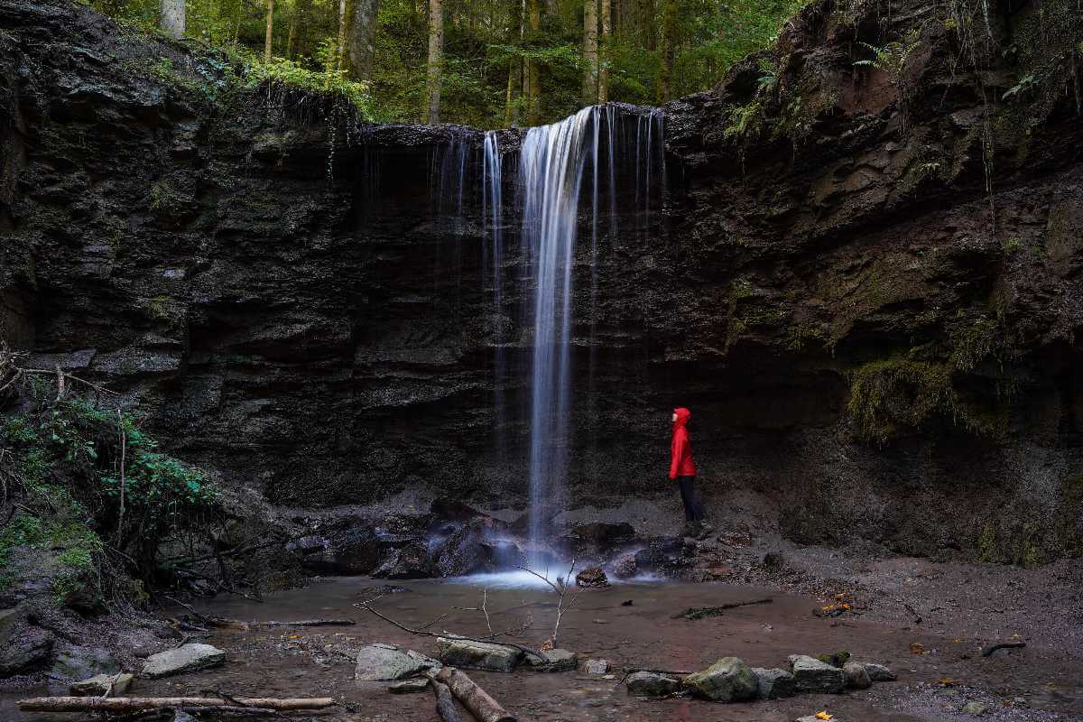 Ausflugsziele Stuttgart: eine Frau steht unter dem Hörschbachwasserfall im Wald